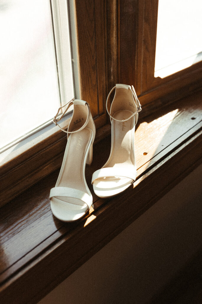 Bride shoes resting on a windowsill while getting ready for a Door County sailboat wedding