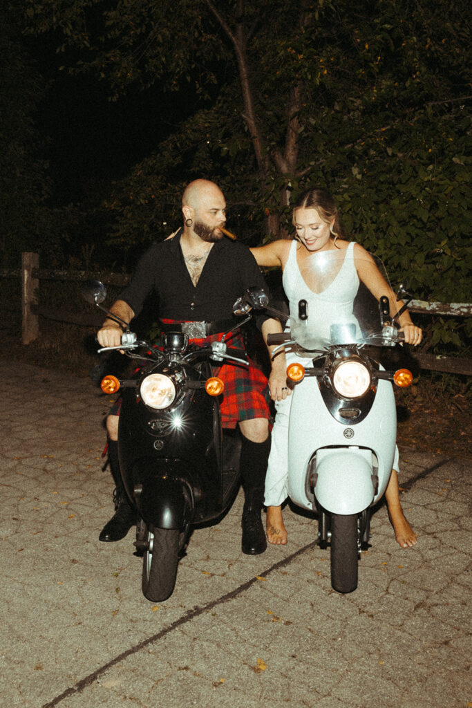 Bride and groom riding mopeds together at night after their Door County wedding celebration