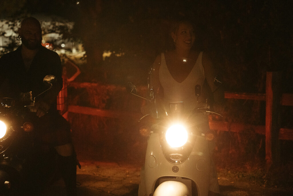 Warm light from headlights of bride on a moped during wedding reception 