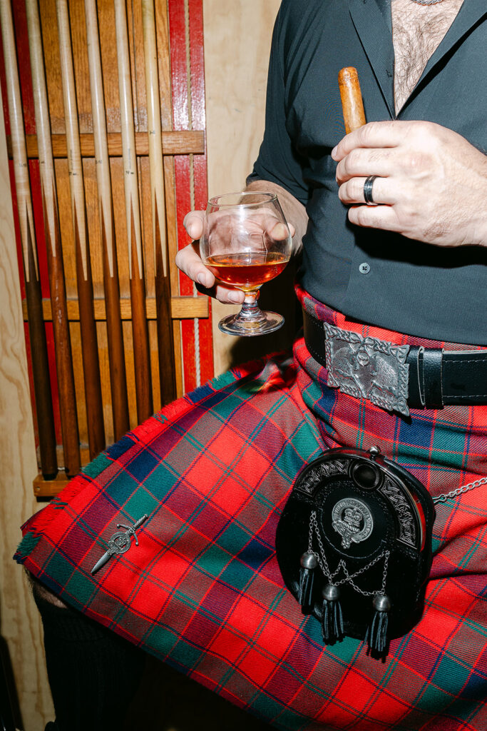 Groom wearing a traditional kilt with a drink in his hand 