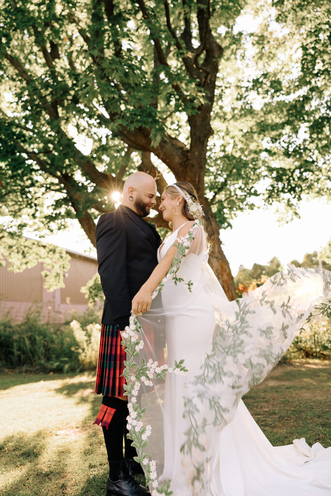 Bride and groom standing together as the veil flows during Door County wedding portraits