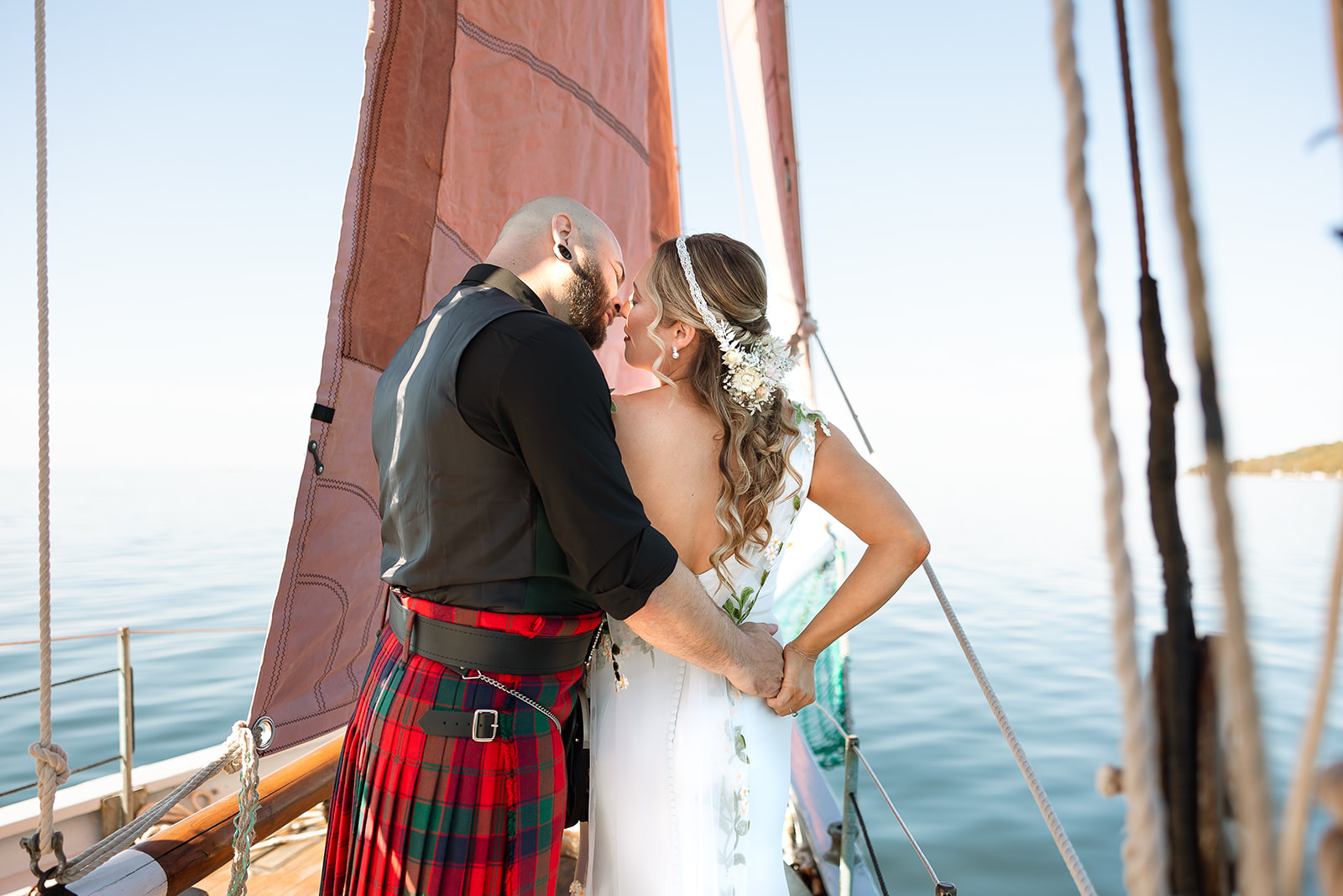 Bride and groom kissing aboard a sailboat during their intimate Door County wedding on Lake Michigan