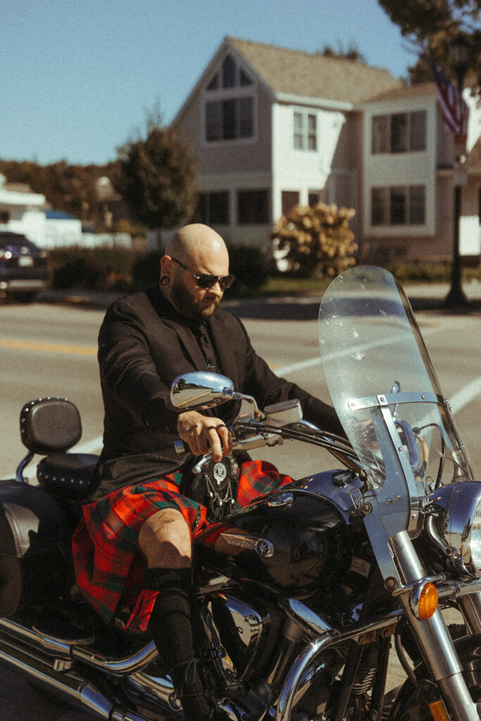 Groom in his kilt getting off his motorcycle to go to his wedding at Sister Bay marina