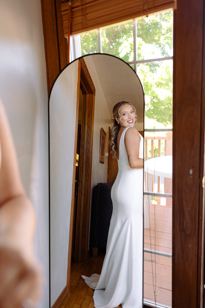 Bride sees herself in her dress in the mirror before her ceremony in Door County on a sailboat