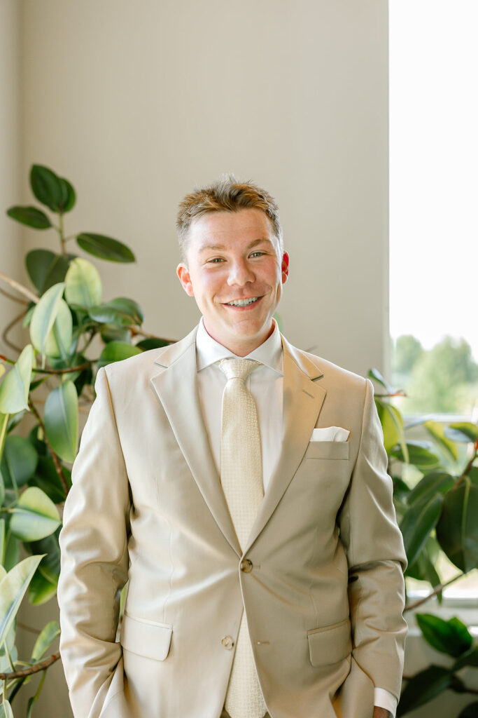 Groom smiling in a light suit before his relaxed Door County wedding at the Kress Pavilion