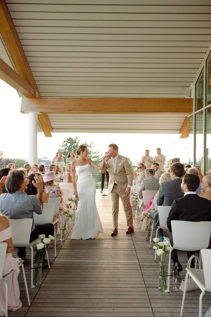 Groom kidding bride's hand in the aisle after wedding ceremony in Door County