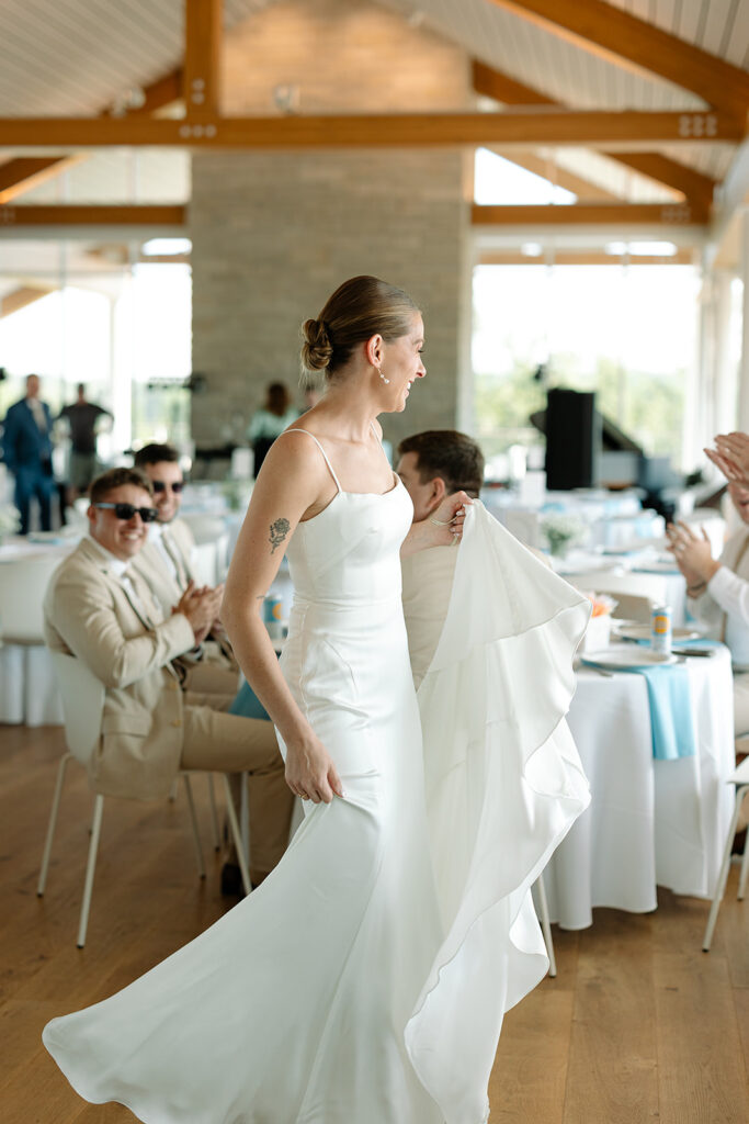 Bride showing off dress to groomsmen at Kress Pavilion