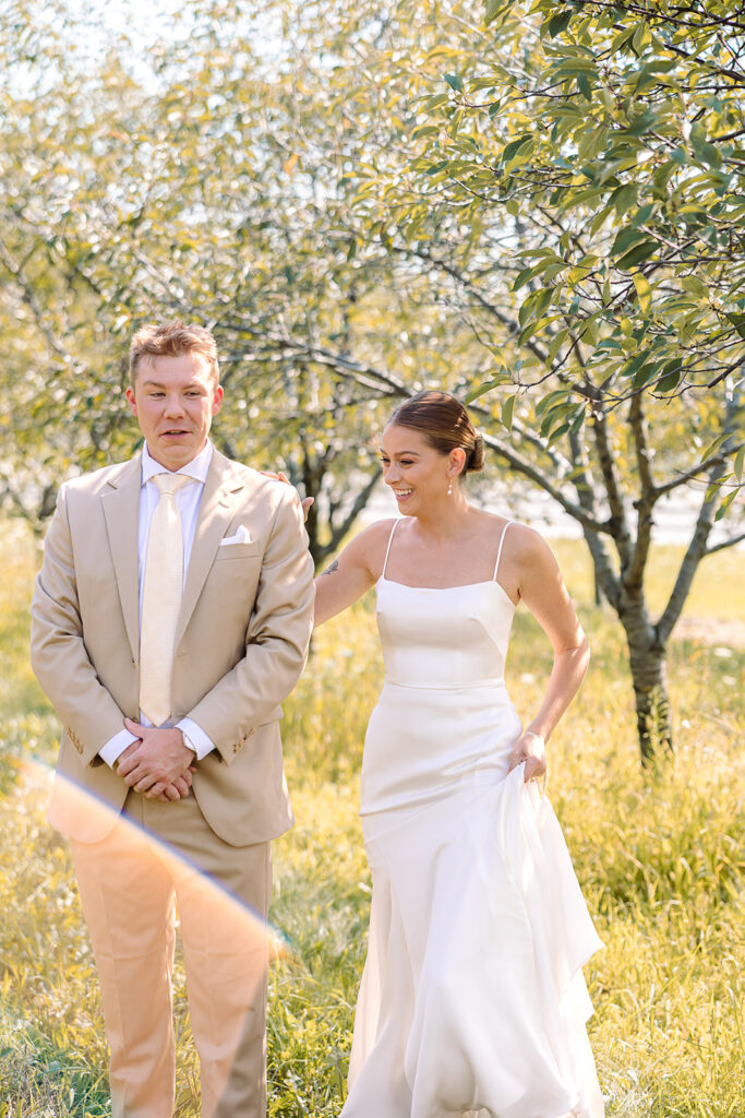 Bride sneaking up on groom for their first look at Kress Pavilion
