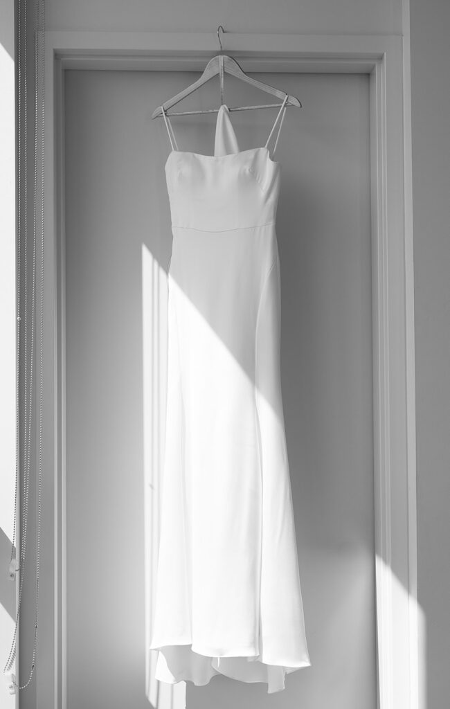 Wedding dress hanging in a soft natural light before a Door County wedding day