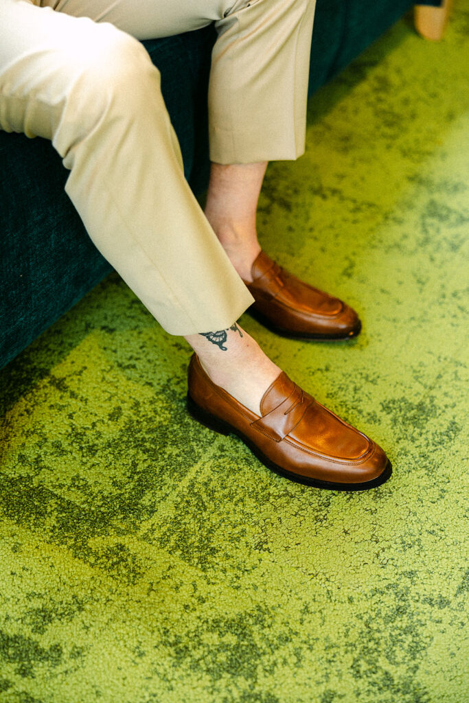 Groom getting ready in brown leather shoes during a relaxed Door County wedding day