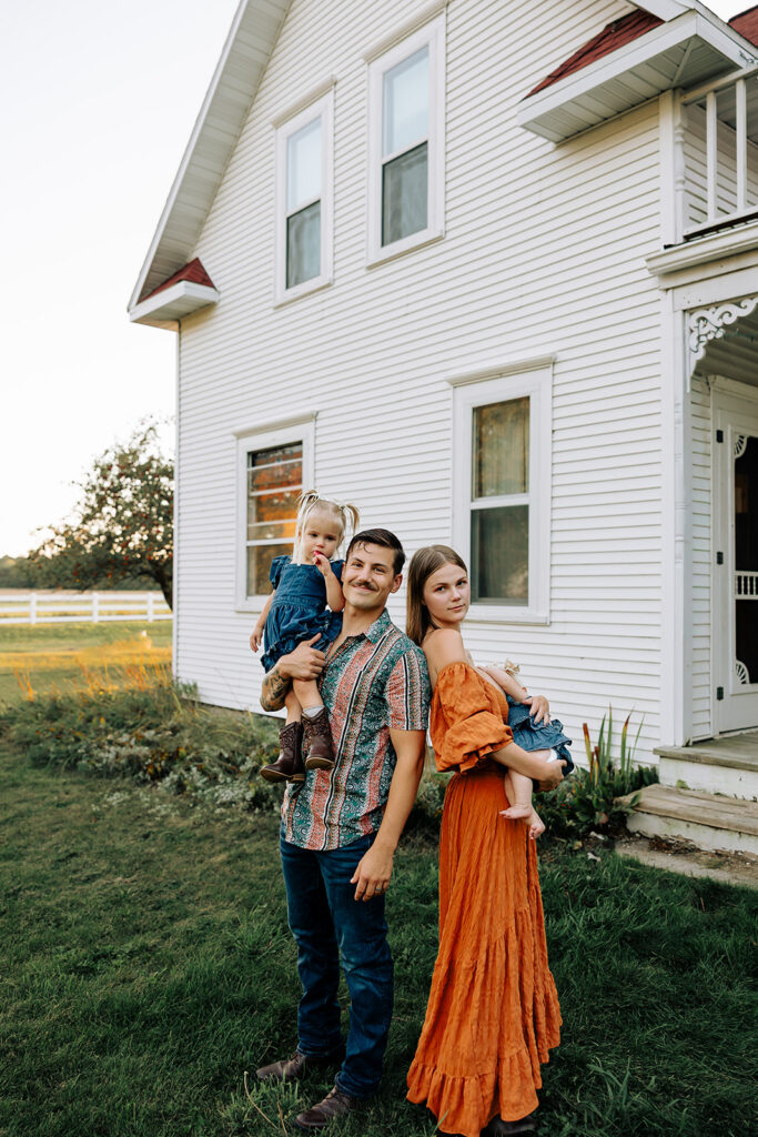 Family standing together on a farm during a fall family photo session in Door County, Wisconsin, photographed in a candid and relaxed style.